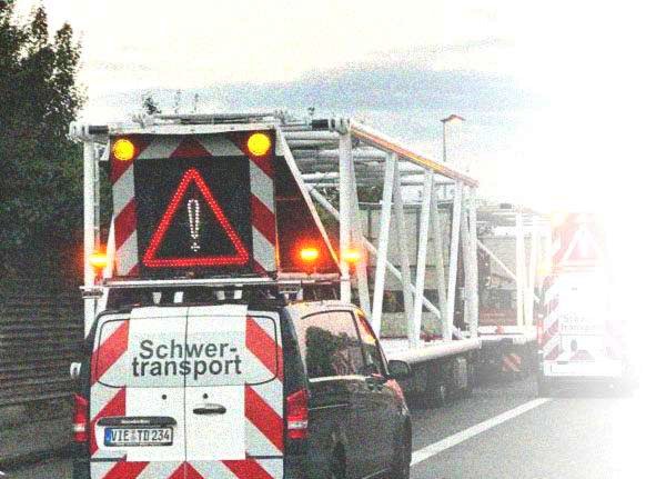 Begleitfahrzeug BF3 mit Wechselverkehrszeichen-Anlage hinter einem Schwertransport auf der Autobahn